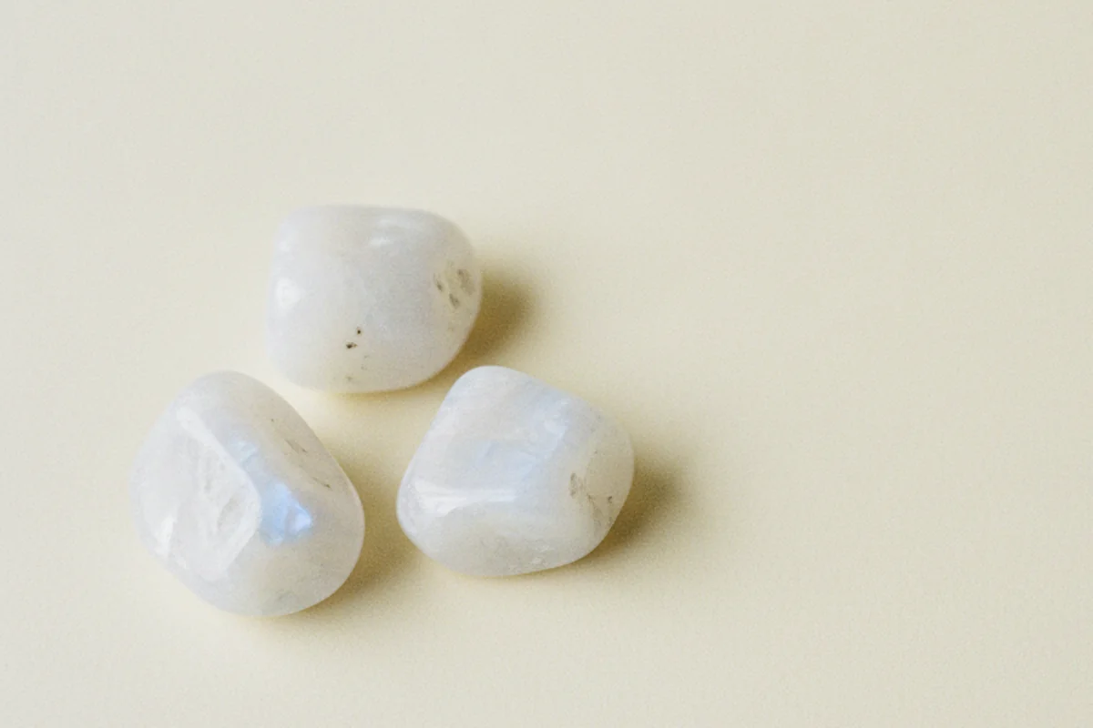 Piedras de luna pulidas con su brillo azulado sobre fondo crema