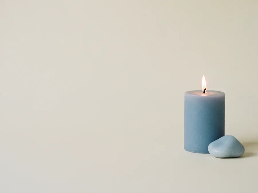 Vela azul encendida con una piedra azul lisa a su lado